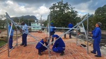 Trabajadores de ETECSA instalando paneles solares en una azotea
